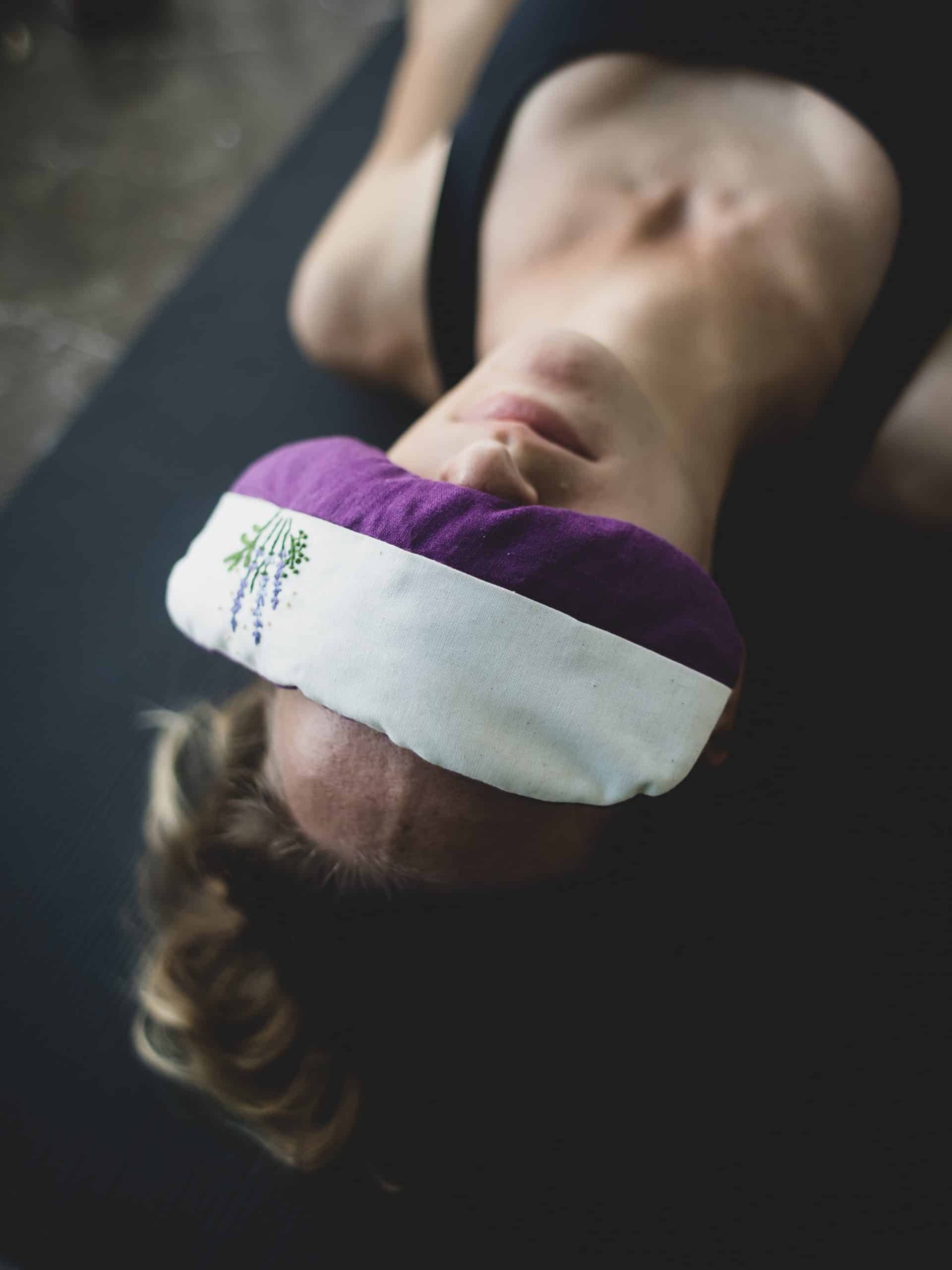 vrouw in yoga houding met lavendel oogmasker